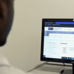A black man uses a computer at the Focus office, to look at jobs on the job board.